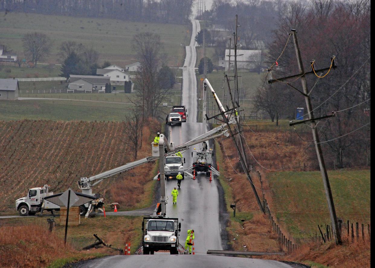 Utility crews work to reset utility poles Monday on Moreland Road near Apple Creek that were blown over the roadway Saturday during a windstorm.
