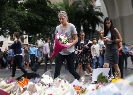 A woman places a floral tribute for those who died in the Sydney cafe siege, near the site of the incident, in Martin Place December 16, 2014. REUTERS/Jason Reed