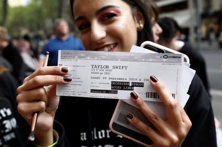 A fan of Taylor Swift holds up her ticket prior to a concert performance at the Olympia Theatre in Paris