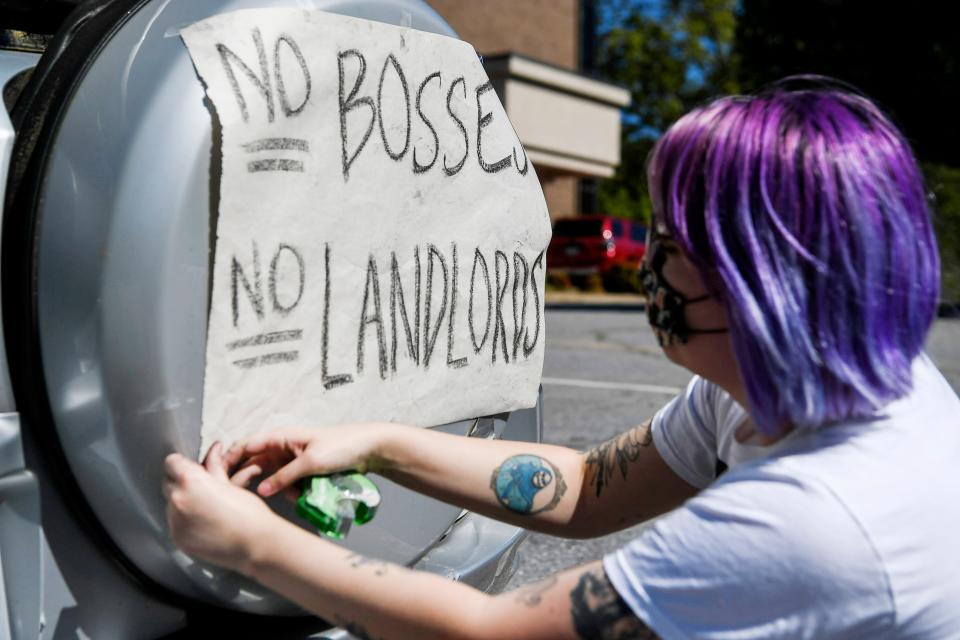 An Asheville area resident tapes a sign onto the back of a car during a protest over rents in May 2020. "I'm worried about my fellow tenants who are out of a job," said Bee, who was placed on paid leave amid COVID-19.