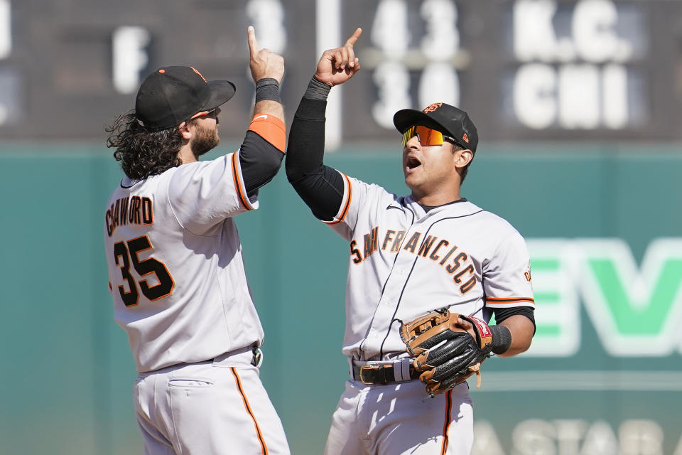 San Francisco Giants' Brandon Crawford, left, celebrates with Donovan Solano after they defeated the Oakland Athletics in a baseball game in Oakland, Calif., Sunday, Aug. 22, 2021. (AP Photo/Jeff Chiu)