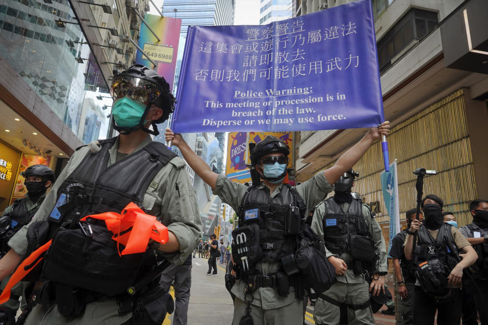 In this July 1, 2020, file photo, police display a public announcement banner showing the warning to protesters in Causeway Bay before the annual handover march in Hong Kong. A national security law enacted in 2020 and COVID-19 restrictions have stifled major protests in Hong Kong including an annual march on July 1. (AP Photo/Vincent Yu, File)