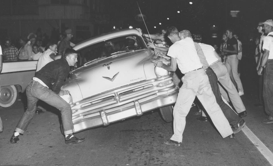 FILE - An angry mob tries to overturn a car carrying Black passengers in Clinton, Tenn., in a file photo from Aug. 31, 1956. Gene Herrick, a retired Associated Press photographer who covered the Korean War and is known for his iconic images of Martin Luther King Jr., Rosa Parks and the trial of the killers of Emmett Till in the early years of the Civil Rights Movement, died Friday, April 12, 2024. He was 97. (AP Photo/Gene Herrick, File)