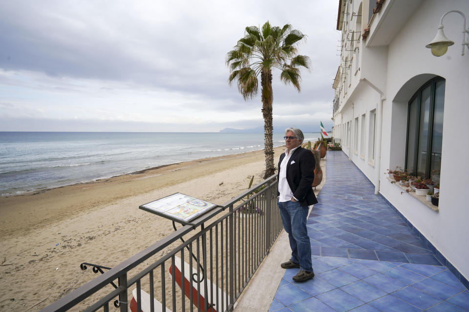 In this picture taken on Tuesday, April 28, 2020, Leone La Rocca, Leone La Rocca, president of Sperlonga tourism association, looks at the empty beach from the terrace of his hotel, in Sperlonga, a fashionable seaside town about 120km (80 miles) south of Rome. Though Italy is gradually reopening from a two-month lockdown, there is no word on when and how beach establishments can open for visitors. (AP Photo/Andrew Medichini)