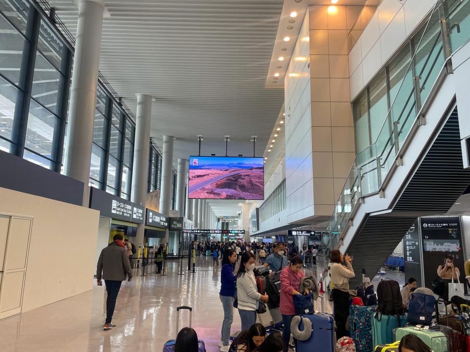 Travelers stand inside the Narita International Airport.