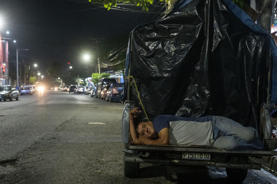 A man rests on the tailgate of his truck as he waits for the release of a family member detained under the ongoing "state of exception", outside a detention center in San Salvador, El Salvador, Tuesday, Oct. 11, 2022. President Nayib Bukele and his allies in congress launched a war against gangs and suspended constitutional rights. Nearly seven months later, this state of exception is still widely popular. (AP Photo/Moises Castillo)