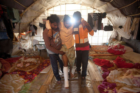FILE PHOTO: Bangladeshi worker Mohamed (C), 25, is helped by colleagues into a tent following a shooting incident in the of town of Manolada, Greece, April 18, 2013. REUTERS/Giorgos Moutafis/File Photo