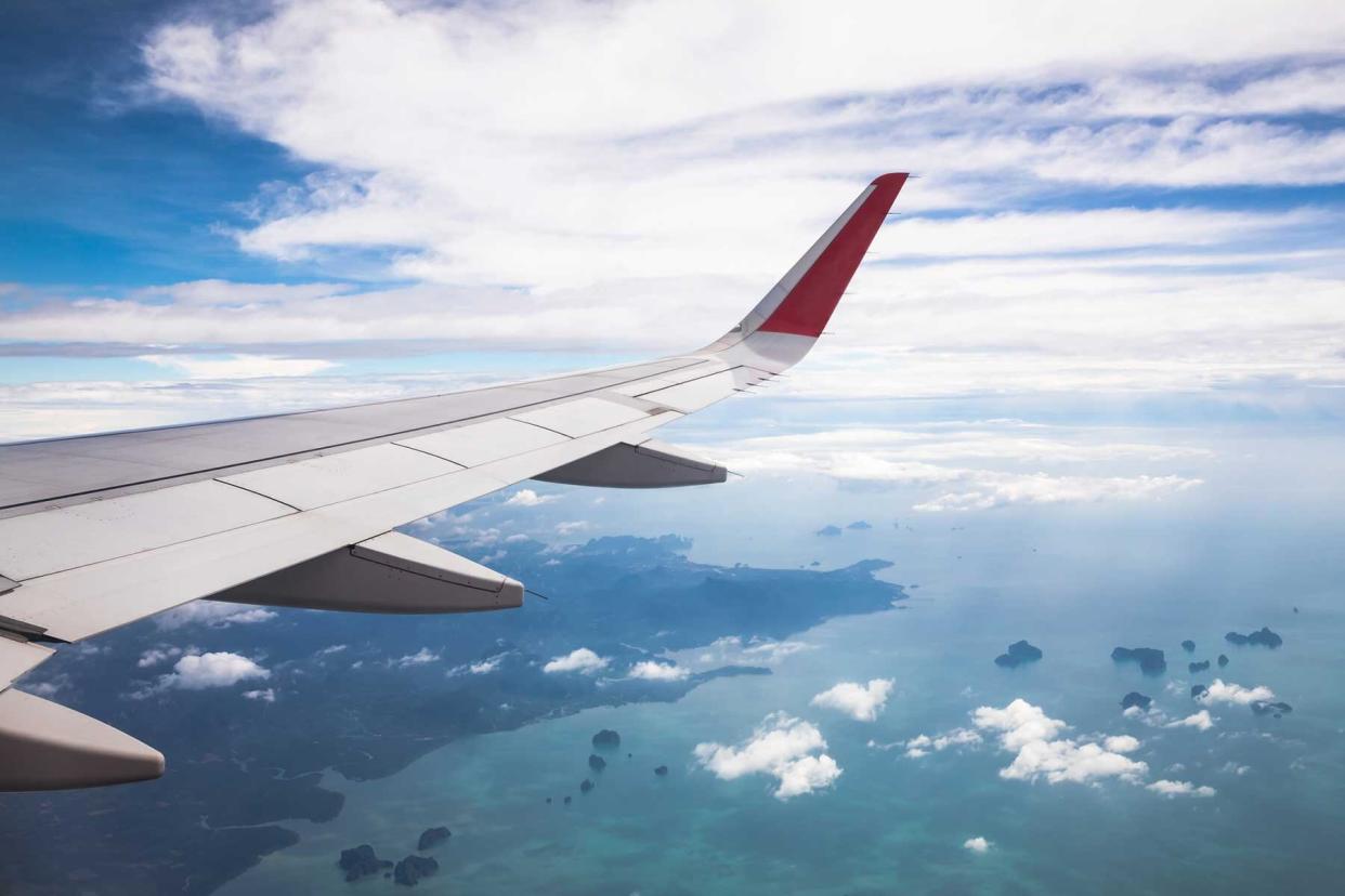 Airplane wing in air over sea and land