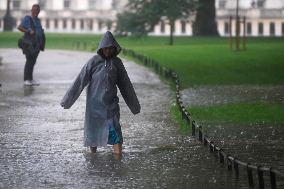 <p>A woman walks through a flooded path in St James's Park in central London. Thunderstorms bringing lightning and torrential rain to the south are set to continue until Monday, forecasters have said. Picture date: Sunday July 25, 2021.</p>
