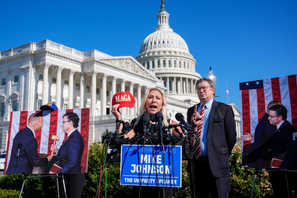 Representatives Marjorie Taylor Greene (centre) and Thomas Massie (right) pictured on 1 May calling for the House to oust Speaker Mike Johnson while standing with pictures of Mr Johnson and Democratic House leader Hakeem Jeffries. The pair has criticised Mr Johnson for working with Democrats (AP)