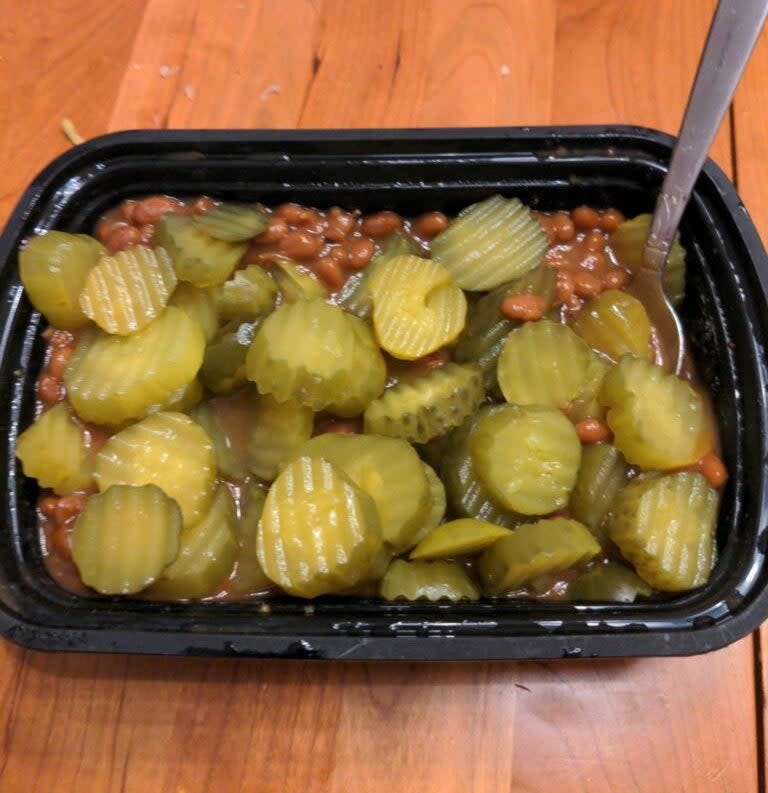 sliced pickles and canned beans mixed together in a plastic takeout container