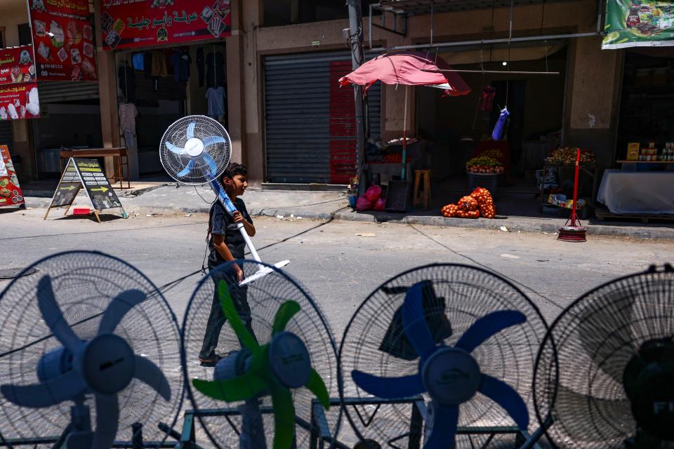 A young boy carries home a battery-powered fan amid a heat wave and electricity shortage in Gaza City, on July 19, 2023.