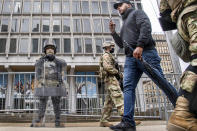 An unidentified pedestrian walks between members of the National Guard as they stand guard in front of the Philadelphia Municipal Services Building in Philadelphia, Pa., Friday, Oct. 30, 2020. (Jose F. Moreno/The Philadelphia Inquirer via AP)