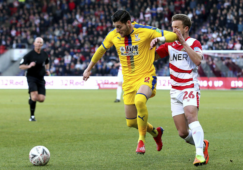 Crystal Palace's Joel Ward, left, and Doncaster Rovers' James Coppinger, during their English FA Cup fifth round soccer match at the Keepmoat Stadium in Doncaster, England, Sunday Feb. 17, 2019. (Richard Sellers/PA via AP)