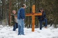 Mourners stand near a wooden cross on Highway 395 near Burns, Oregon on January 29, 2016, at the location where Robert "LaVoy" Finicum was shot dead and others were arrested