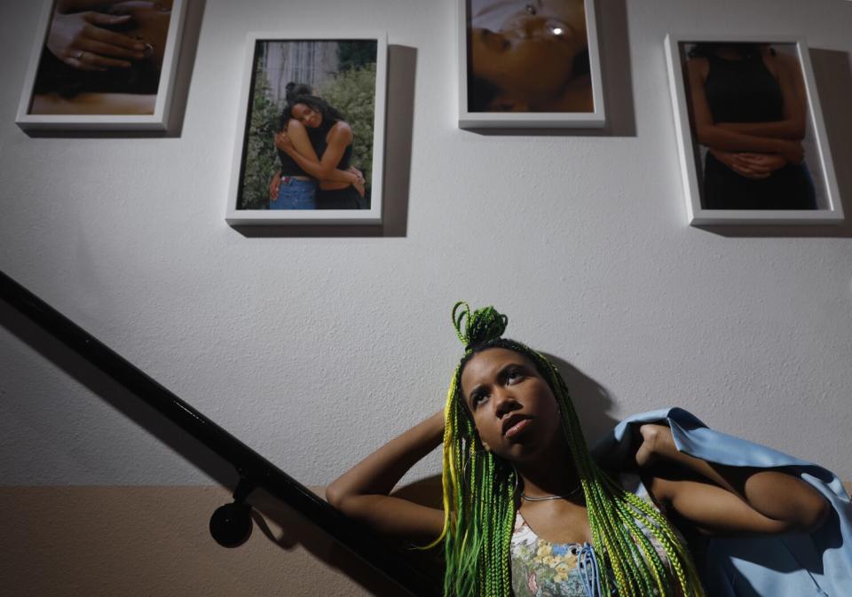 A person leans against a bannister with four works of art above them.