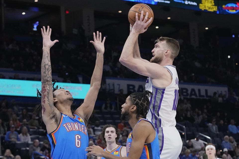 Sacramento Kings forward Domantas Sabonis, right, shoots over Oklahoma City Thunder forward Jaylin Williams (6), between guard Josh Giddey, center and guard Isaiah Joe, second from right, in the first half of an NBA basketball game Sunday, Feb. 26, 2023, in Oklahoma City. (AP Photo/Sue Ogrocki)