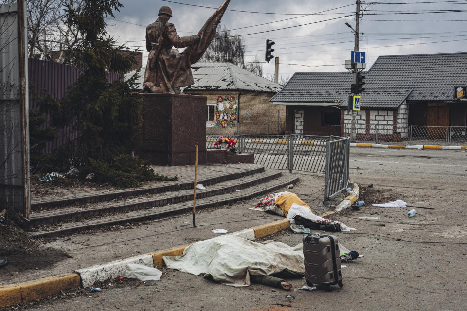 The bodies of several people killed by Russian shelling lie covered in the street in Irpin. 