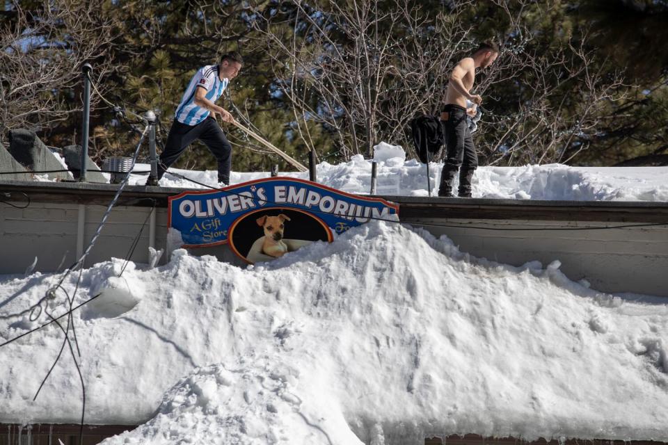 Men shovel snow off the roof of a Big Bear Village gift shop