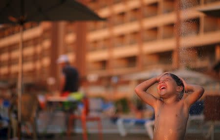 A Palestinian boy takes shower as he enjoys the warm weather with his family at the Blue Beach Resort in Gaza July 30, 2015. REUTERS/Mohammed Salem