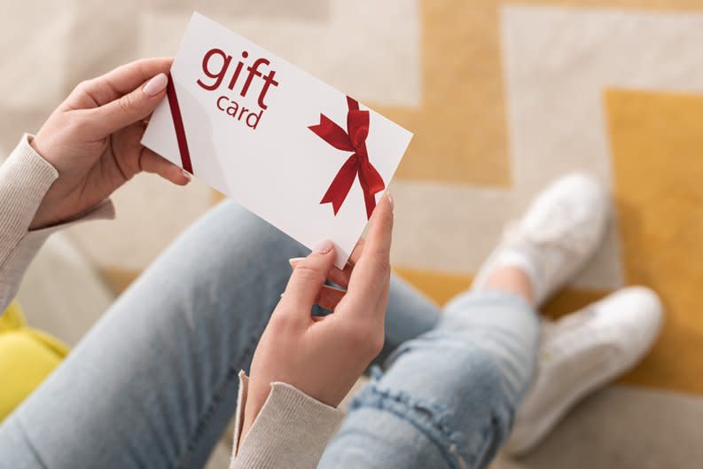 A woman holds a generic gift card.