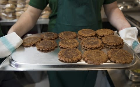 A cook carries a tray of burger patties - Credit: Jason Alden/Bloomberg