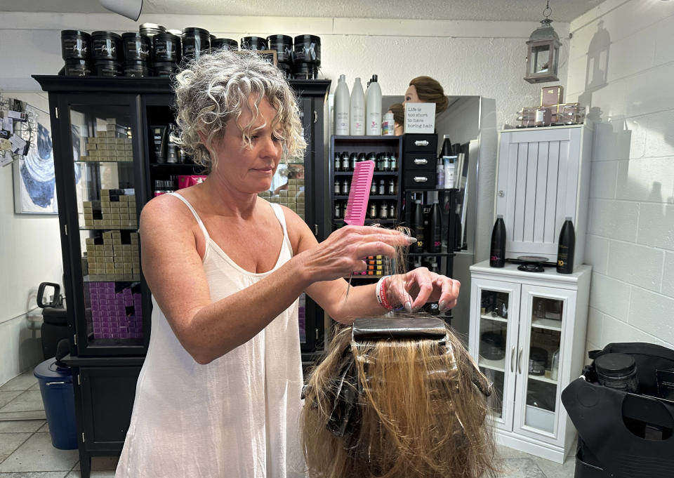 Christine Geiger cuts a customer's hair at her salon Wednesday, July 12, 2023, in Traverse City, Mich. Geiger has drawn criticism after posting on social media that anyone identifying as other than a man or woman is not welcome at her business. Geiger tells The Associated Press she believes small businesses should be able to serve whom they wish. City officials are investigating whether she is violating an anti-discrimination ordinance. (AP Photos/John Flesher)