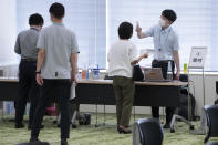 Employees of the beverage maker Suntory register to receive shots of the Moderna COVID-19 vaccine at their office building as the company began its workplace vaccination Monday, June 21, 2021, in Tokyo. Thousands of Japanese companies began distributing COVID-19 vaccines to workers and their families Monday in an employer-led drive reaching more than 13 million people that aims to rev up the nation's slow vaccine rollout. (AP Photo/Eugene Hoshiko)