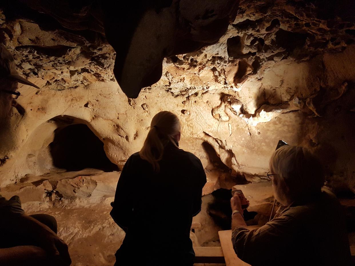 Researchers stand in the La Roche-Cotard cave looking at engravings made by Neanderthals