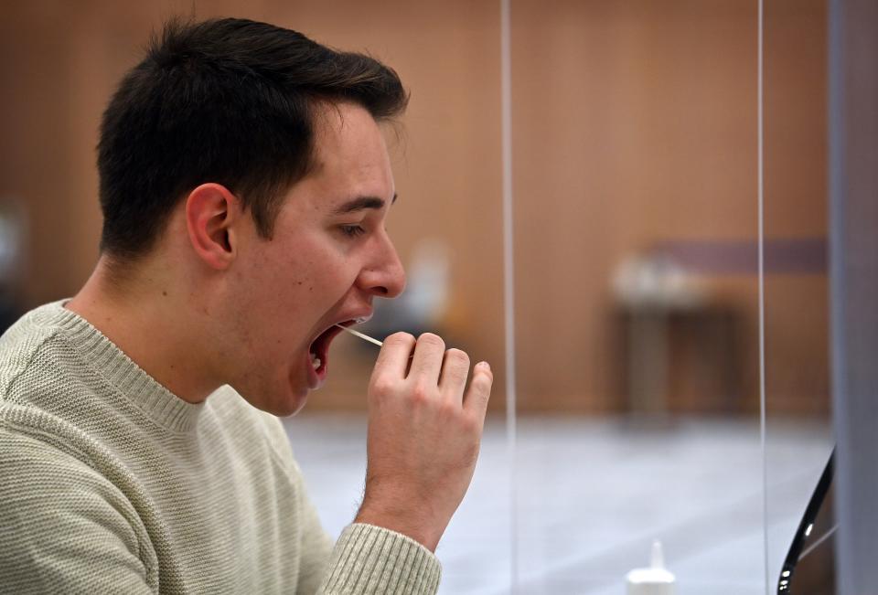 Tom O'Neill, a 23 year old computer science student at Hull University, takes a swab for a lateral flow Covid-19 test at the campus sports facilities on January 4, 2021, as students return to the university. - Britain -- one of the worst-affected countries by the global health crisis, with more than 75,000 deaths -- is pinning its hopes on the jab as the mainstay of its mass vaccination drive. (Photo by Paul ELLIS / AFP) (Photo by PAUL ELLIS/AFP via Getty Images)