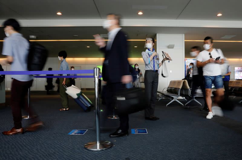 A staff member of All Nippon Airways wearing a protective mask and a face shield works at a boarding gate amid the coronavirus disease (COVID-19) outbreak at Haneda airport in Tokyo