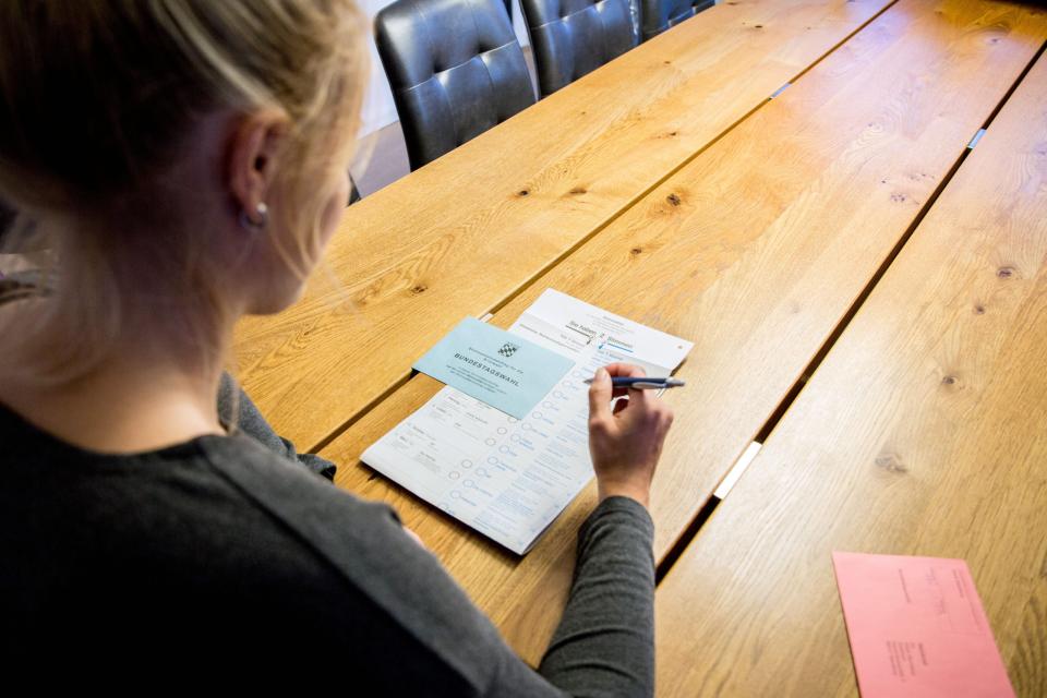 Eine Frau schaut sich den aktuellen Stimmzettel sowie die Wahlunterlagen der Briefwahl zur Bundestagswahl am Sonntag 26. September 2021 an.