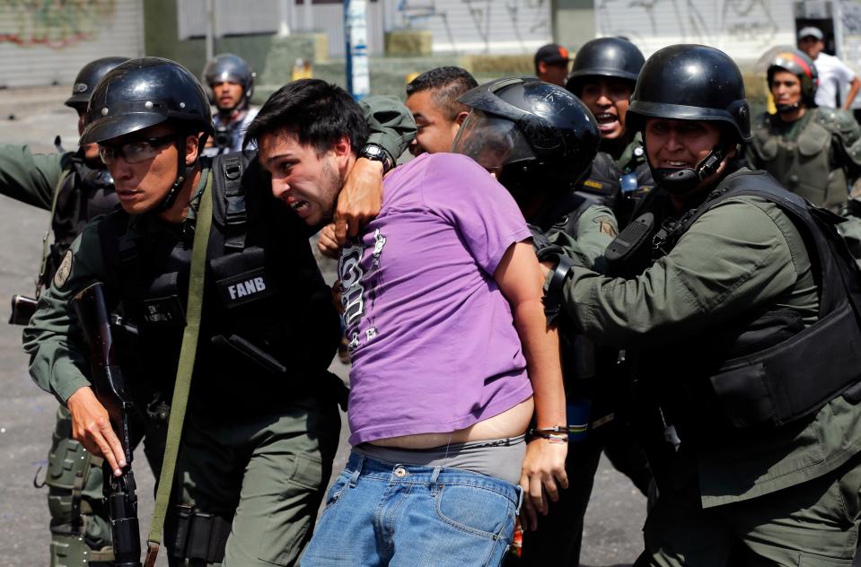 Bolivarian National Guards arrest an anti-government protester during clashes between armed motorcyclists and protesters in the Los Ruices neighborhood of Caracas, Venezuela, Thursday, March 6, 2014. Venezuelan officials say a National Guard member and a civilian were killed in the clash between residents and armed men who tried to remove a barricade placed by anti-government protesters. (AP Photo/Fernando Llano)