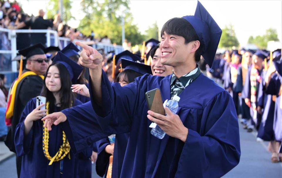 Merced College graduate Katsuya Sasaki waves to someone in the crowd as he makes his way into Stadium ’76 for the school’s 60th commencement ceremony on Friday, May 26, 2023.