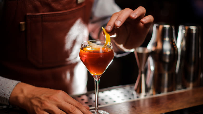 bartender applying garnish to cocktail