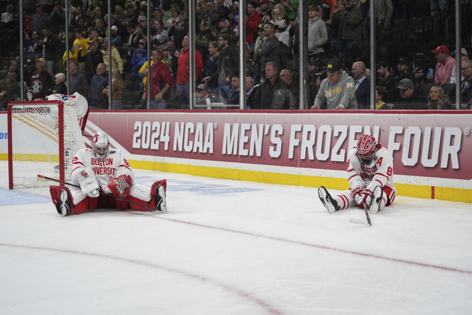 Boston University goaltender Mathieu Caron, left, and defenseman Cade Webber (8) sit on the ice after an overtime loss to Denver in a semifinal game at the Frozen Four NCAA college hockey tournament Thursday, April 11, 2024, in St. Paul, Minn. (AP Photo/Abbie Parr)