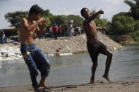 Jóvenes migrantes se pelean por unos cigarrillos en la orilla del río Suchiate, en el lado mexicano, cerca de Ciudad Hidalgo, México, en la frontera con Guatemala, el martes 21 de enero de 2020. (AP Foto/Marco Ugarte)