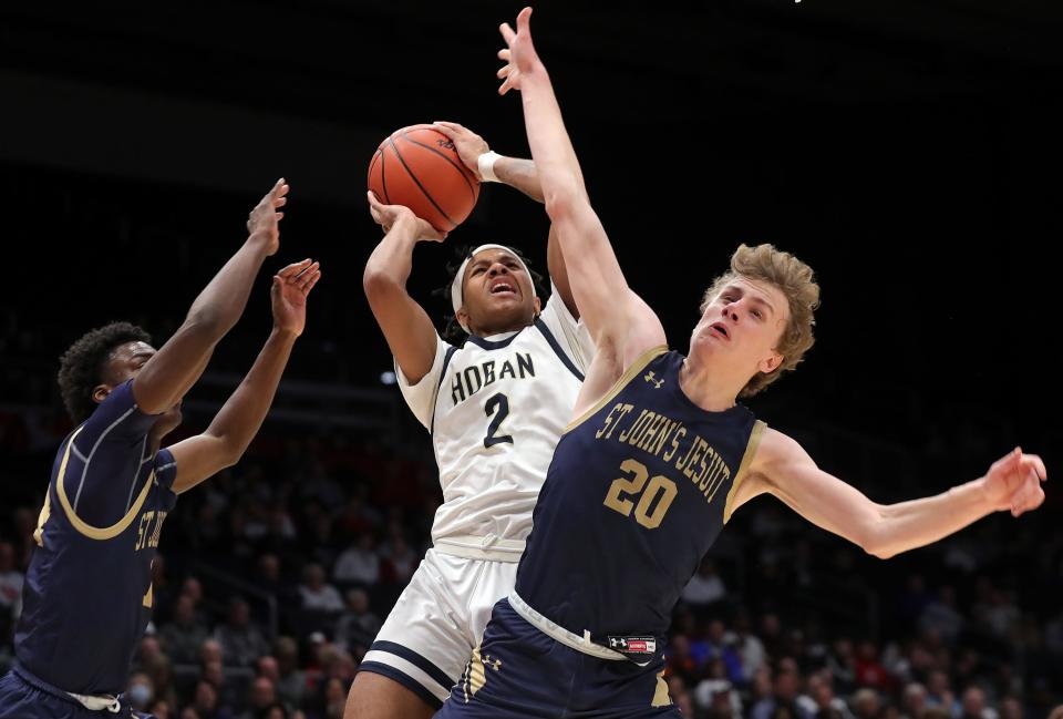 Hoban guard William Scott Jr., center, attempts a shot between St. John's Jesuit's Joseph Taylor, left, and Mitchell Michalak, right, during the second half of a Division I state semifinal basketball game at UD Arena, Saturday, March 18, 2023, in Dayton, Ohio.