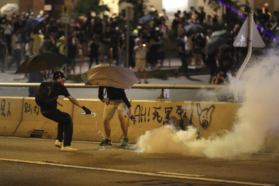 Protestors pour water to douse a tear gas shell in Hong Kong, Saturday, Sept. 28, 2019. A pro-democracy rally in downtown Hong Kong has ended early amid sporadic violence, with police firing tear gas and a water cannon after protesters threw bricks and Molotov cocktails at government offices. (AP Photo/Vincent Thian)