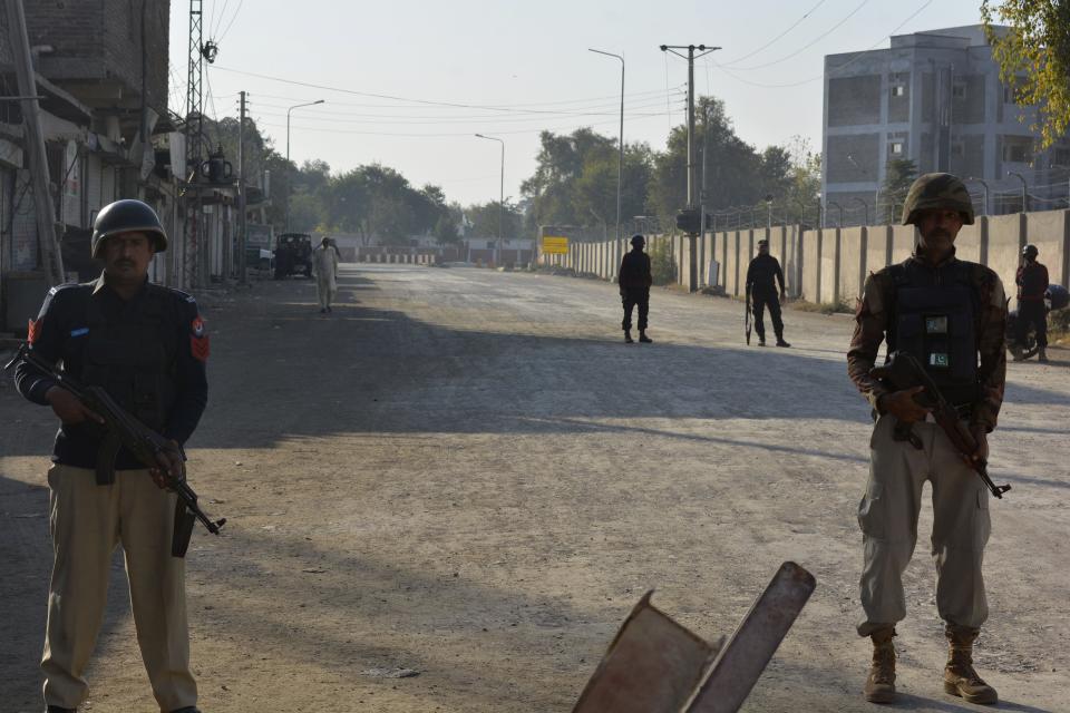 Security officials guard a blocked road leading to a counter-terrorism center after security forces starting to clear the compound seized earlier by Pakistani Taliban militants in Bannu, a northern district in the Pakistan's Khyber Pakhtunkhwa province, Tuesday, Dec. 20, 2022. Pakistan's special forces on Tuesday stormed the counter-terrorism center to free several security officials who were taken hostage earlier this week by a group of detained Pakistani Taliban militants, security officials said. (AP Photo/Muhammad Hasib)