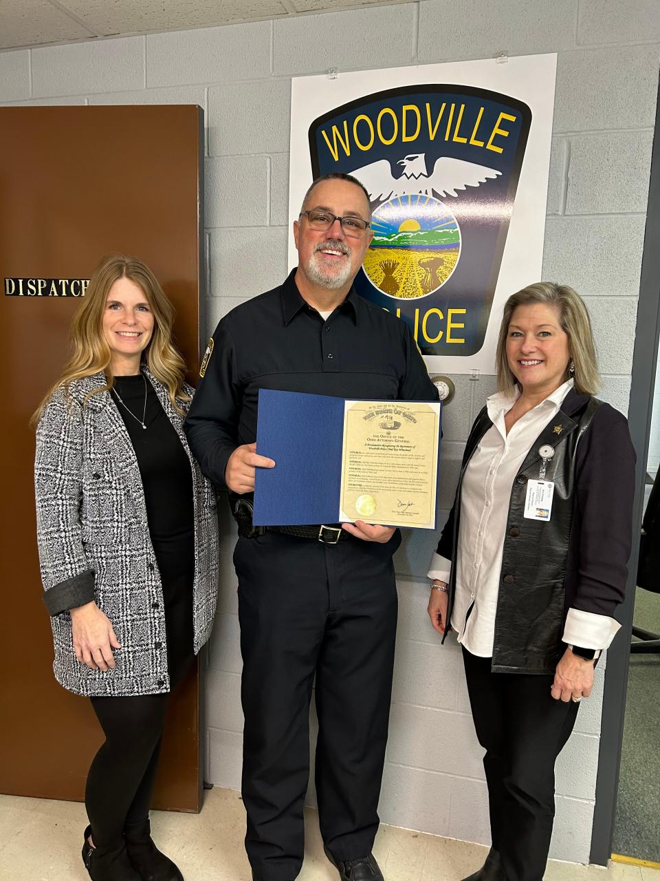 Chief Roy Whitehead, center, standing with his wife, Lori Whitehead, right, receives a certificate from Regional Director Kim Priestap from the Ohio Attorney General's Office.