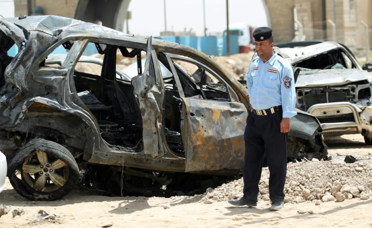 An Iraqi policeman looks at damaged cars at the site of a suicide bomb attack, claimed by the Islamic State group, at a checkpoint northeast of the capital Baghdad