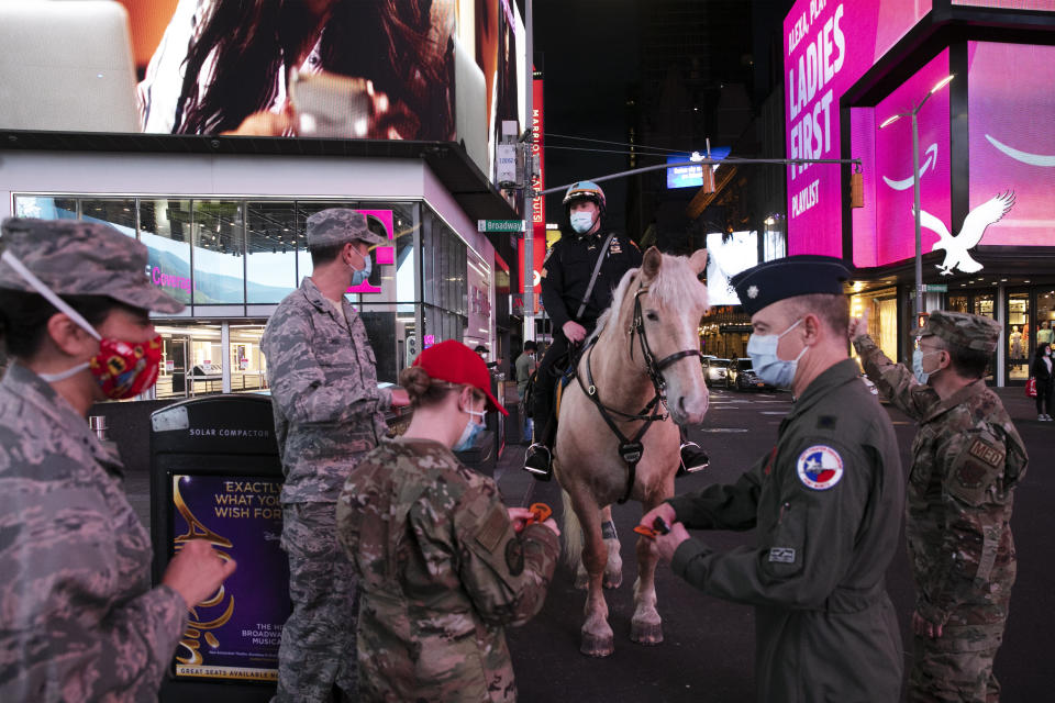 In this Saturday, May 2, 2020 photo, a mounted New York City police officer wearing a mask greets visiting Air Force officers in New York during the coronavirus pandemic. (AP Photo/Mark Lennihan)