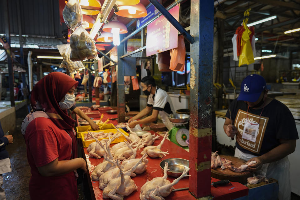 A woman wearing a face mask to help curb the spread of the coronavirus shops at a poultry stall in a wet market in downtown Kuala Lumpur, Malaysia, Friday, April 24, 2020. Malaysia, along with neighboring Singapore and Brunei, has banned popular Ramadan bazaars where food, drinks and clothing are sold in congested open-air markets or road-side stalls. The bazaars are a source of key income for many small traders, some who have shifted their businesses online. (AP Photo/Vincent Thian)