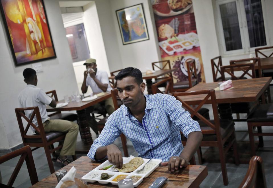 Customers eat inside a restaurant run by the Tihar Jail authorities on Jail Road in west Delhi July 21, 2014. "Tihar Food Court" in west Delhi, a rehabilitation effort kicked off by the Tihar prison, opened in the first week of July on an "experimental basis" while awaiting formal clearances. It is sited half a km (0.6 mile) away from prisoners' dormitories. With a spacious interior lined with wooden tables and walls adorned with paintings done by prisoners, the 50-seat restaurant has been praised for the polite behaviour of its employees, who were trained by a prestigious nearby hotel management school. Picture taken July 21, 2014. REUTERS/Anindito Mukherjee (INDIA - Tags: CRIME LAW FOOD SOCIETY)