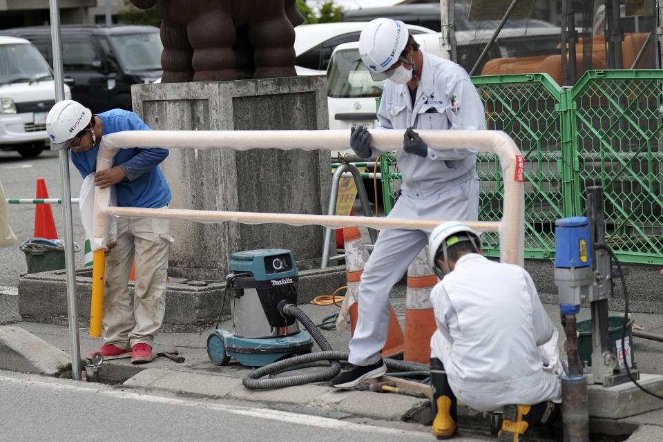 Workers set up a barricade near the Lawson convenience store Tuesday, April 30, 2024, at Fujikawaguchiko town, Yamanashi Prefecture, central Japan. (AP Photo/Eugene Hoshiko)