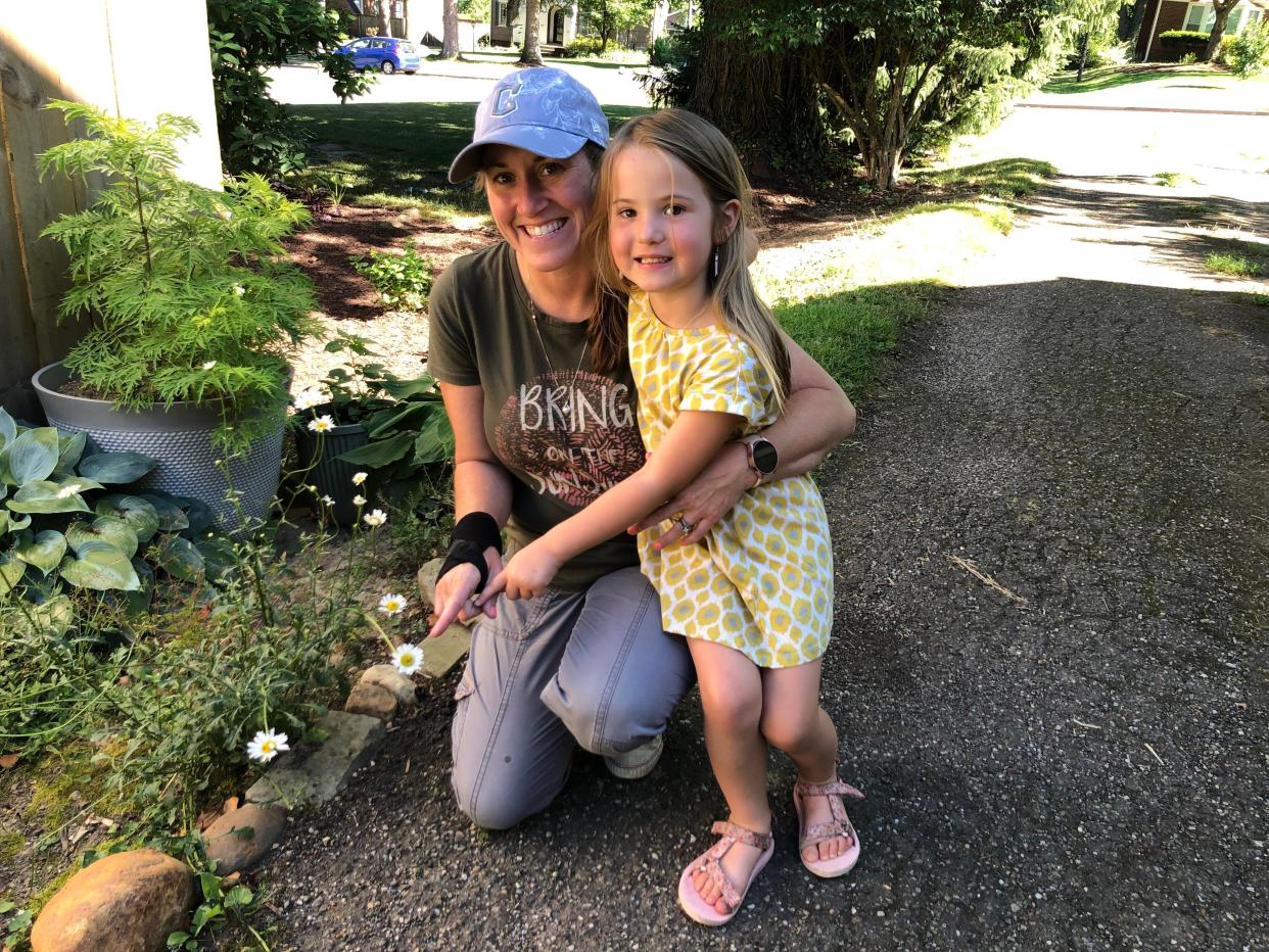 Katie Kent-Horton of Louisville and her daughter Alana, 5, point to a daisy in Kent-Horton's parents' driveway in Canton where Kent-Horton saw a smiley face on Thursday.