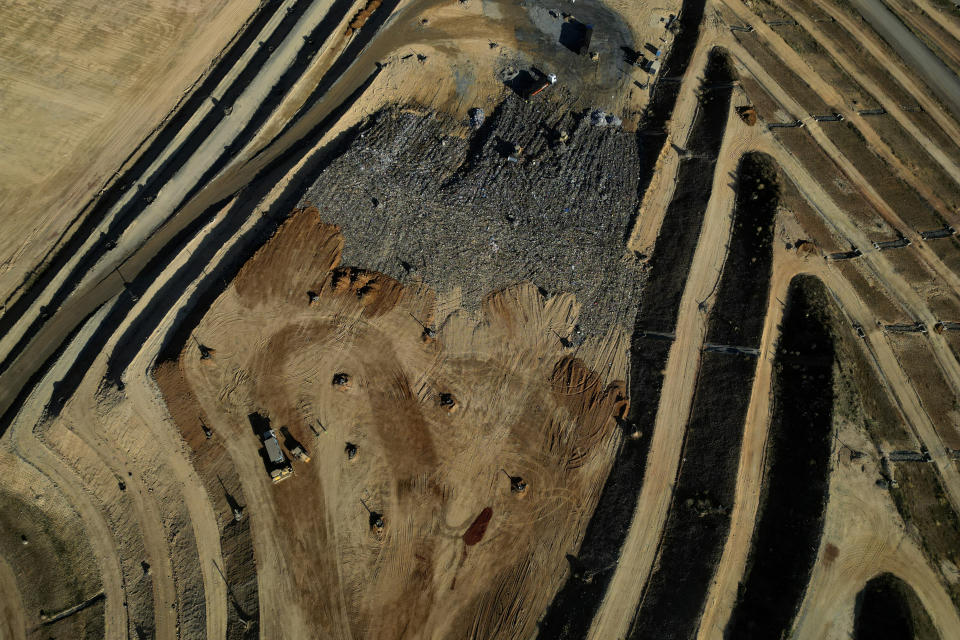 Tractores y camiones extienden capas de basura en un vertedero en Brasilia, Brasil, el 4 de junio de 2024. De acuerdo con el gobierno federal, los estados y las ciudades tienen hasta agosto para reducir el impacto medioambiental de la recolección de basuras. (AP Foto/Eraldo Peres)