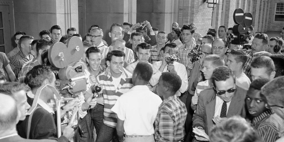 A black-and-white photo from 1957 shows a mob of students blocking a group of Black students from entering North Little Rock High. Cowboys owner Jerry Jones can be seen in a striped shirt, center-left, looking on.