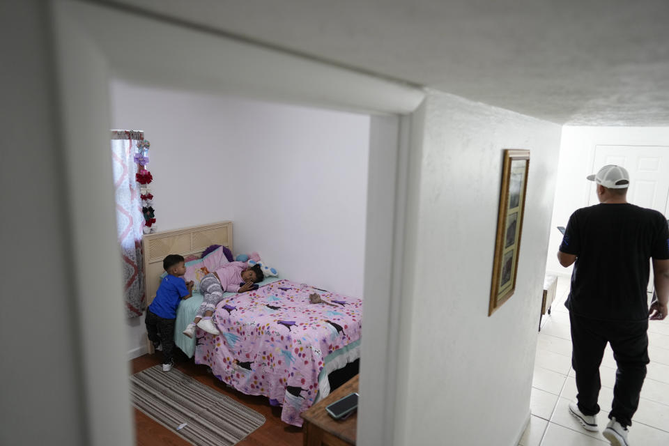 Alexis Llanos, a la derecha, se aleja después de haber permanecido en el cuarto de sus hijos Alexa, de 7 años, y Alexis, de 3, en la casa de Lehigh Acres, en Florida, a la que se mudaron en octubre de 2023, cinco años después de haber salido de Venezuela hacia Colombia por amenazas de muerte, el 27 de diciembre de 2023. La de Llanos es una de las primeras familias de migrantes que llegaron a Estados Unidos legalmente bajo un nuevo programa conocido como "Oficinas de Movilidad Segura", que busca agilizar el proceso de refugiados. (AP Foto/Rebecca Blackwell).